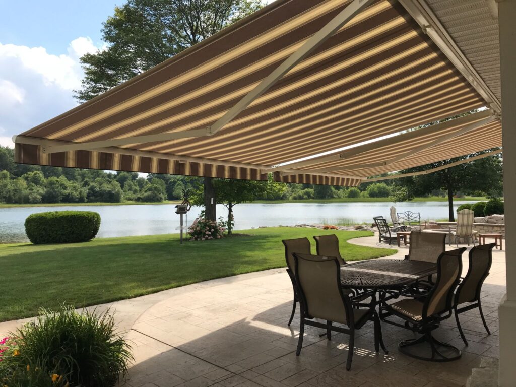 Brown striped Sunesta awning from Designer Awningsm providing shade for an outdoor dining area.