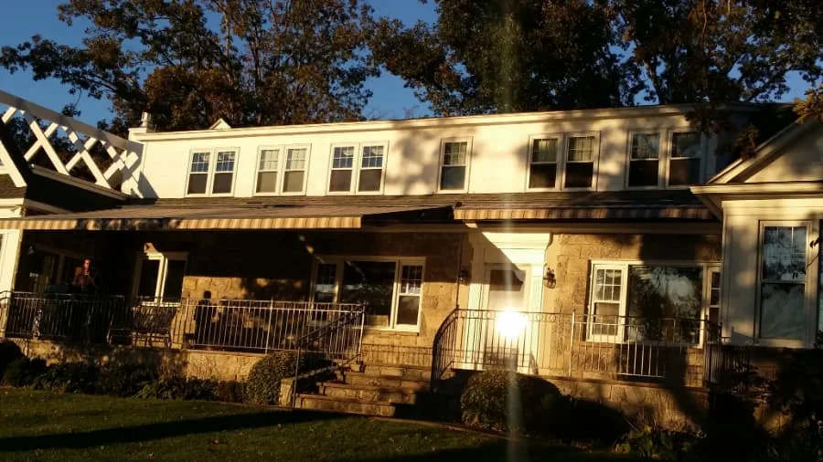 A home with window and porch awnings lit by the setting sun