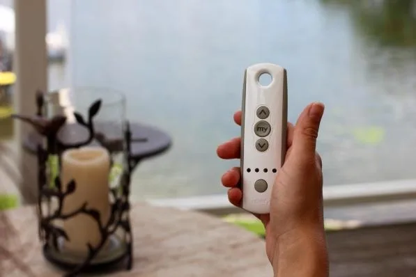 A homeowner holding the remote for a motorized awning