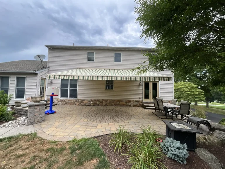 A retractable awning over a paver patio behind a house