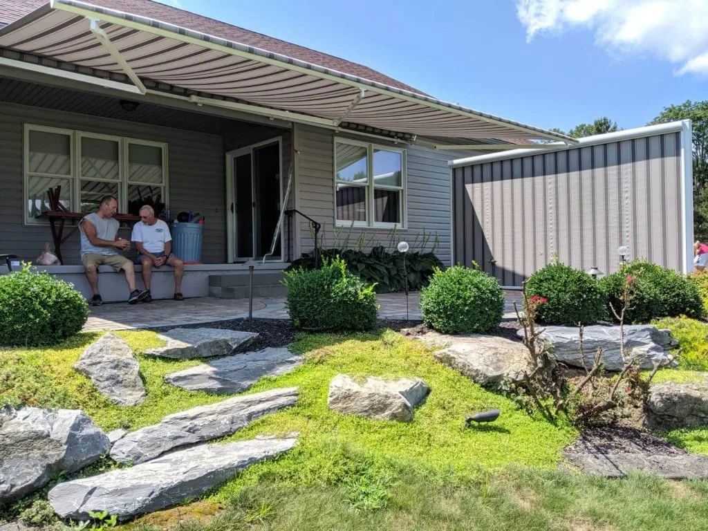 A retractable awning with a side screen shading a couple on a patio