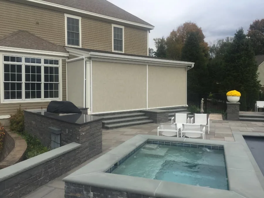A retractable screen installed beside a patio with a hot tub