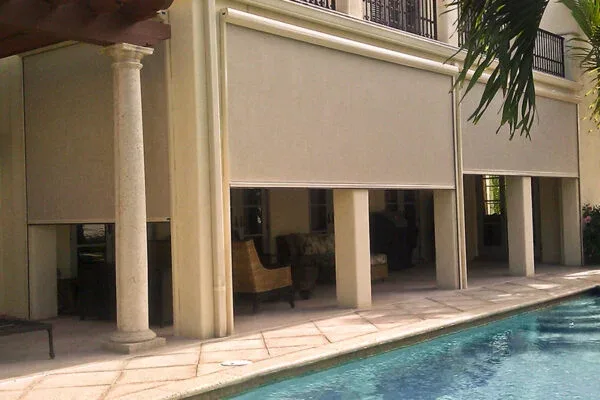 Retractable screens lowered between columns beside a pool
