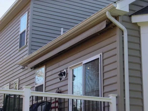 A retracted awning mounted on the back wall of a house