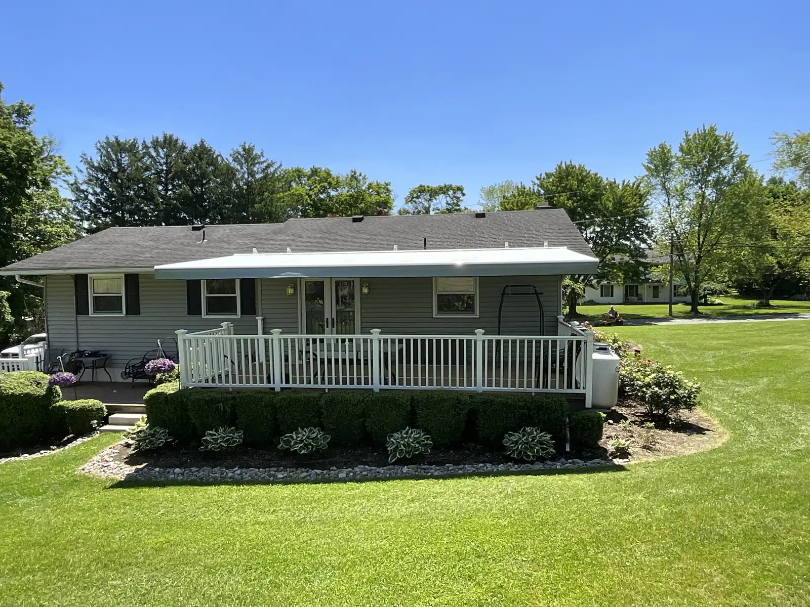 A white retractable awning over a deck on a ranch home
